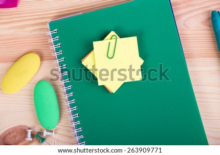Notebooks, pens, and stickers on wooden background