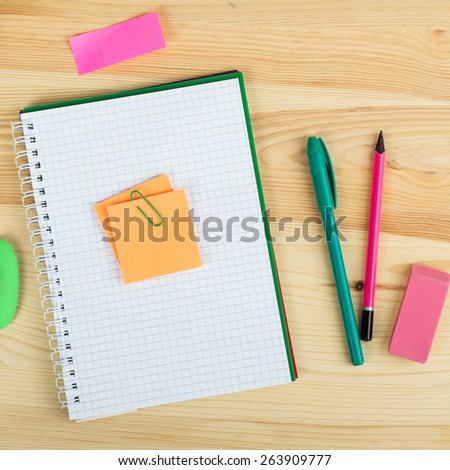 Notebooks, pens, and stickers on wooden background