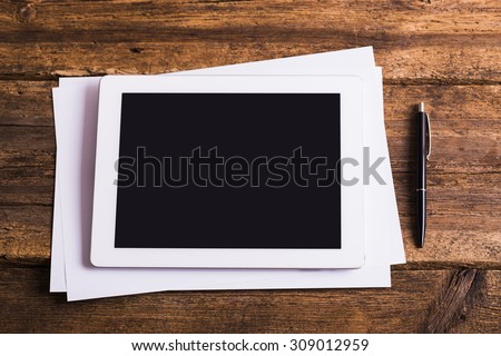 Blank modern digital tablet with papers and pen on a wooden desk. Top view. High quality detailed graphic collage.