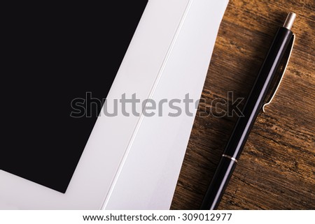 Blank modern digital tablet with papers and pen on a wooden desk. Top view. High quality detailed graphic collage.