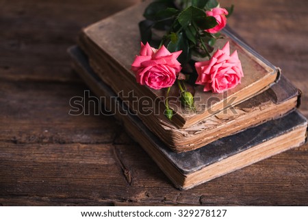 cup of coffee with milk and pink roses and books on the old wooden background