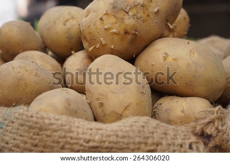 Close up of potatoes in the bag at the market with some potatoes in soft focus and blurry