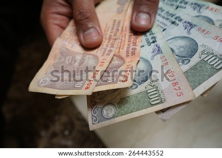 Hand holding a spread of cash in rupee currency. The image was taken in shallow depth of field.