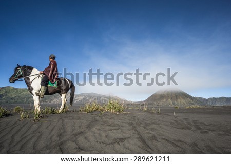 Undefined horse rider transferring tourists around volcano. Mt. Bromo is an active volcano and part of the Tengger massif, in East Java