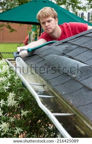 A Man Cleaning Gutters With A Water Hose