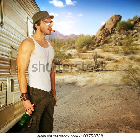 Sexy portrait of a man standing outside RV holding beer in beautiful setting