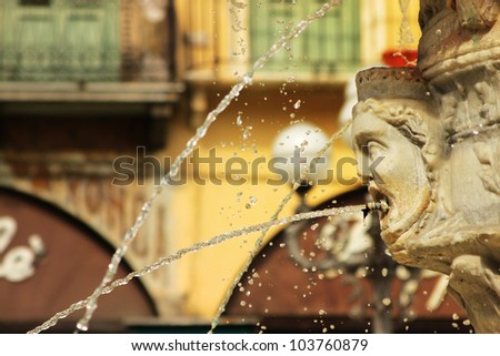 Old world fountain in profile spitting water with background of historic european buildings