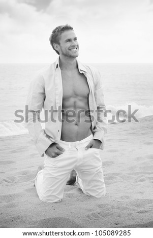 Classic fine art black and white portrait of a relaxed young man with open shirt on vacation at beach