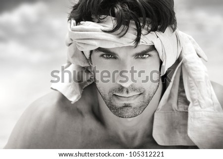 Fine art black and white portrait of a beautiful masculine man outdoors with fabric around head