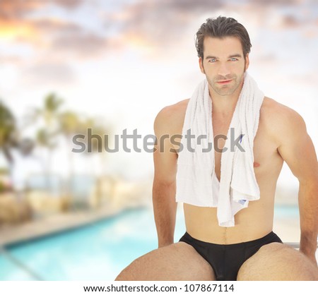 Portrait of a healthy good-looking guy in bathing suit with towel around his neck in beautiful spa resort setting