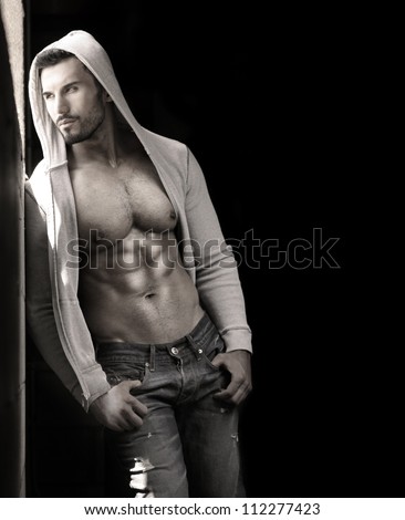 Young handsome macho man with open jacket revealing muscular chest and abs with copy space