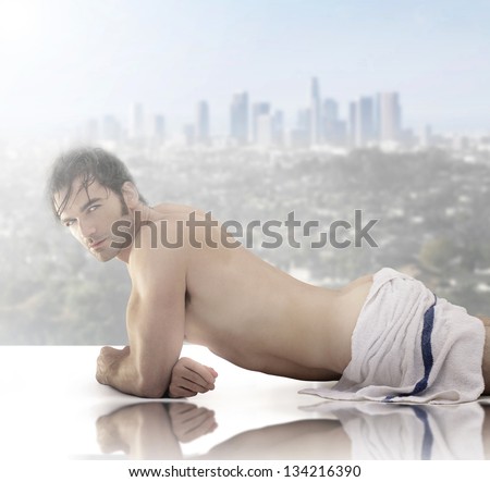 Beautiful male model wrapped in towel laying down against scenic city view background