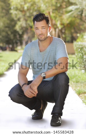 Full body portrait of a young relaxed handsome man on sidewalk outdoors