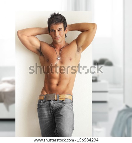 Sexy smiling shirtless male model with muscular body and abs in modern contemporary setting