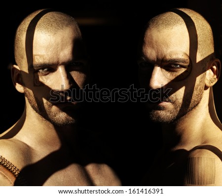 Powerful fine art portrait of two twin male models in darkness with shadows and abstract elements obscuring their faces