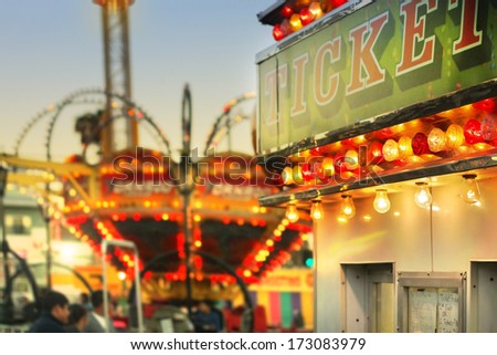 Scene at a classic carnival with a ticket booth in the foreground (focal point on the ticket sign) with overall subtle retro vintage tone and styling
