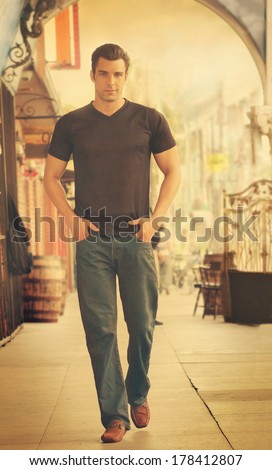 Young male fashion model walking in street scene with retro vintage toning