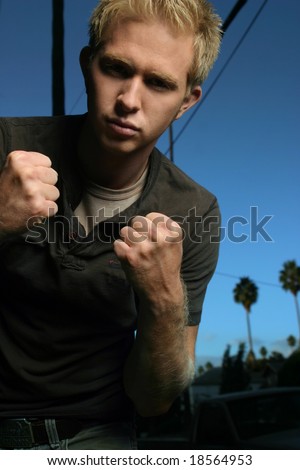 young blond male in fighting stance with blue sky