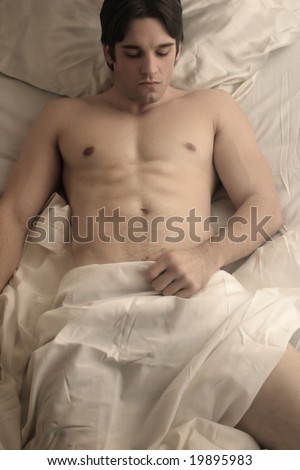 stock photo young naked man in bed with white sheets