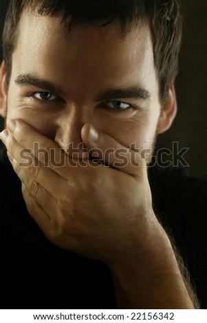 Portrait of man covering face with hand about to laugh