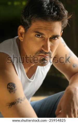 Portrait of a tough guy in white tank top with tattoos