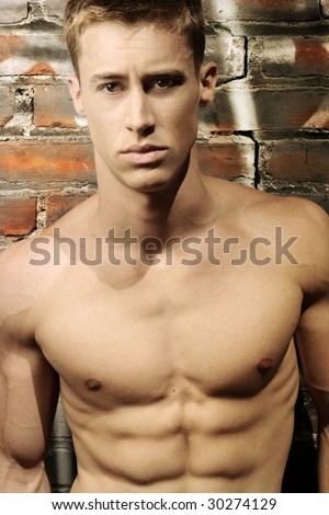 Portrait of a sexy shirtless tough guy against urban brick wall