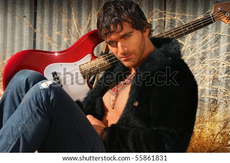 Warm outdoor portrait of a young edgy man with his guitar