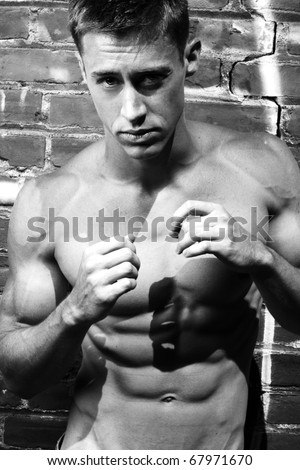 Black and white fine art portrait of a young boxer on the street with brick wall background