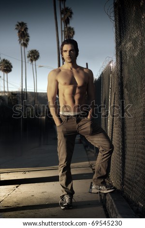 Fashion style portrait of a classic California guy outdoors with golden sunset light and palm trees in the distance