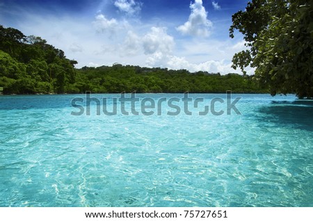 Beautiful secluded cove in the Caribbean featuring turquoise waters and blue sky framed by green vegetation
