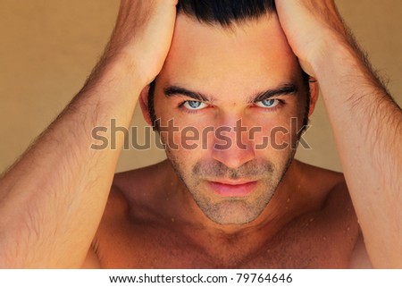Closeup portrait of an attractive male model with hands on his head