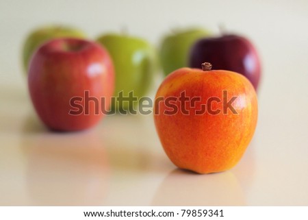 Group of varied colored apples with shallow depth of field against neutral reflective background