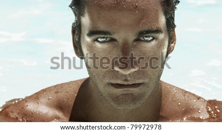 Highly detailed closeup portrait of a young good looking man\'s face with bright catch light reflections in blue eyes against modern wet background