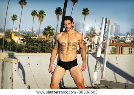 Body portrait in natural light of a young male fitness model in black briefs on Los Angeles rooftop