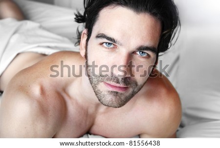 Happy relaxed young good looking man shirtless in bedroom