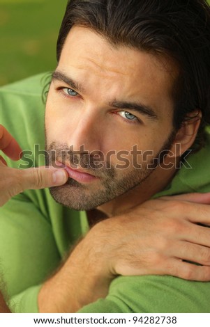 Close-up portrait of a good looking male model with facial expression in green sweater and green background