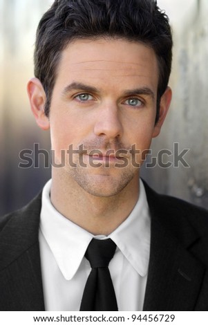Closeup portrait of a young business man in suit and tie against modern background