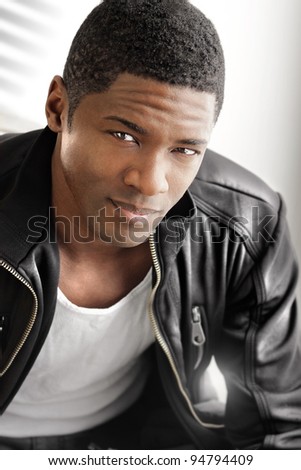 Portrait of a young black man in leather jacket against modern bright background