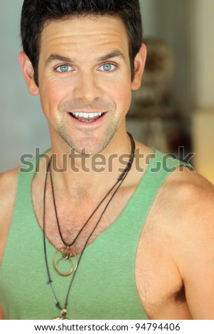 Portrait of a very happy smiling young man in green tank top with bright green eyes