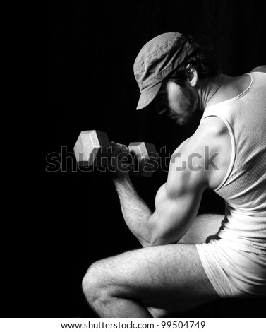 Sexy black and white fitness fashion portrait of very muscular fit male model doing bicep curl against black background