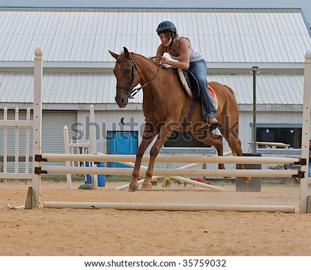 Teen girl jumping a horse over rails.