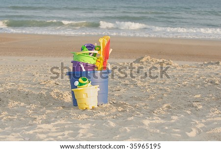 Sand toys on the beach in front of the waves.
