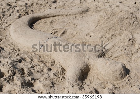 Sand sculpture of a merman with a sea shell belt.