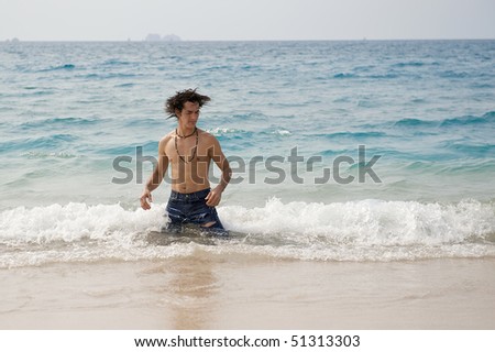 Athletic and muscular man in the surf of the Atlantic Ocean shaking his wet hair.