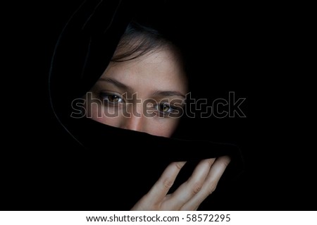 Beautiful ethnic woman with sad eyes, wrapped in a black scarf.