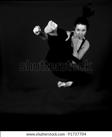 MMA - Female mixed martial arts warrior kicking on a black background.