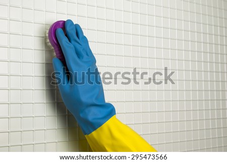 brush for cleaning with hand in blue with yellow glove on the white cells