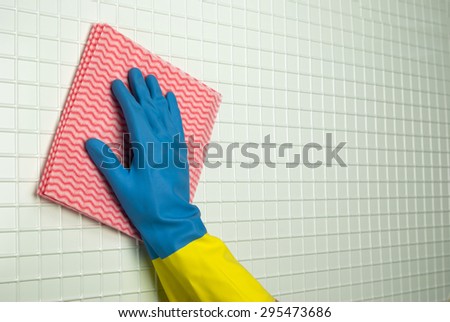 pink rag to clean with a hand in blue with yellow glove on the white cells