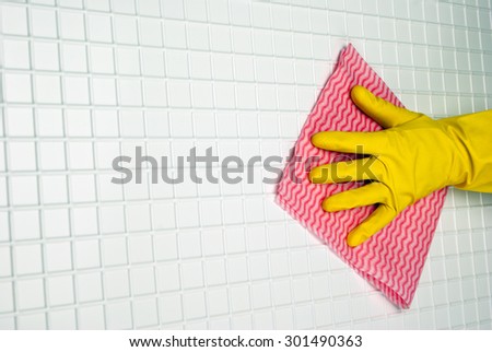 hand in yellow glove with pink rag on the white cells