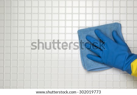 Hand in blue glove with blue cloth on a white tile